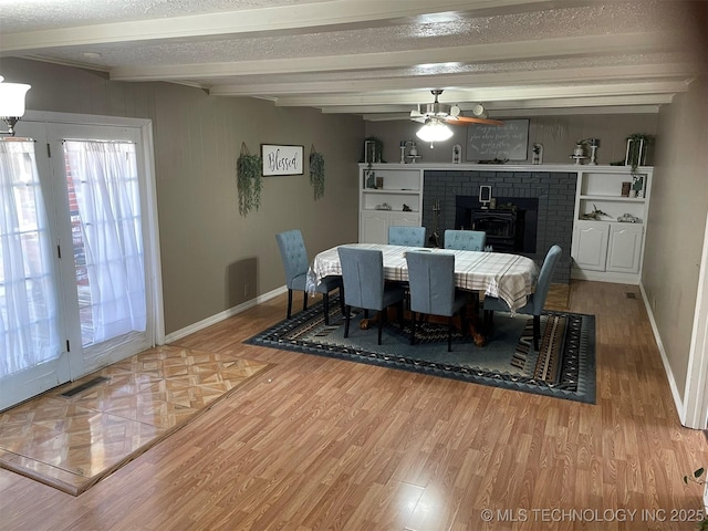 dining space with beam ceiling, ceiling fan, a textured ceiling, and light wood-type flooring