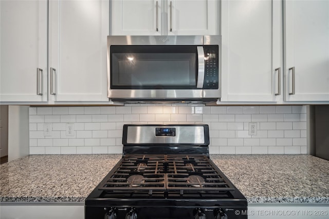 kitchen featuring light stone counters, stainless steel appliances, tasteful backsplash, and white cabinets