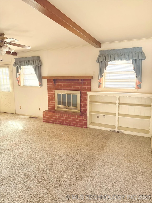 unfurnished living room with a ceiling fan, visible vents, carpet floors, beam ceiling, and a fireplace