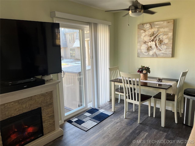 dining area with ceiling fan, a fireplace, and dark hardwood / wood-style flooring