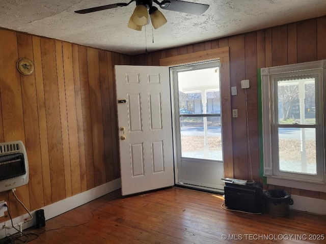 foyer with wood-type flooring, wooden walls, and heating unit