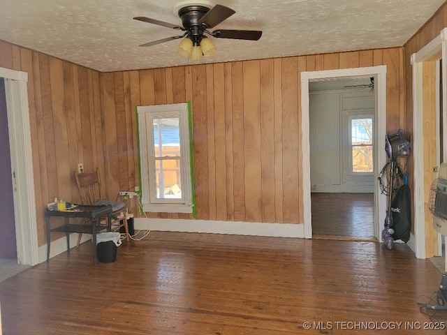 spare room with wooden walls, ceiling fan, dark hardwood / wood-style floors, and a textured ceiling