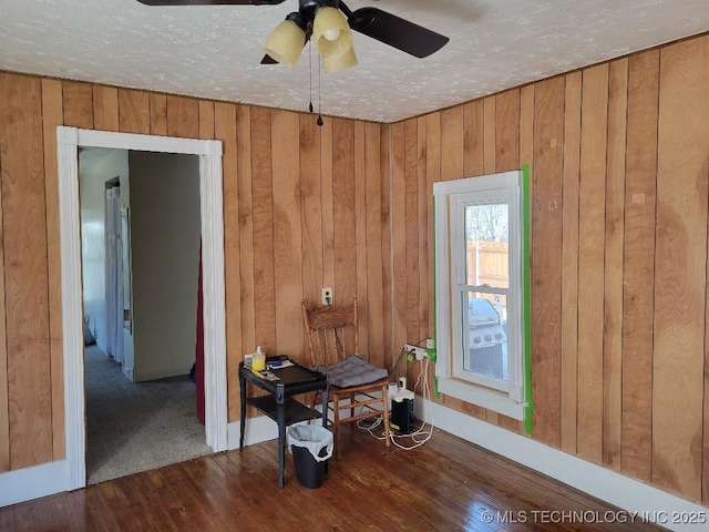 interior space featuring dark hardwood / wood-style flooring, a textured ceiling, and wooden walls