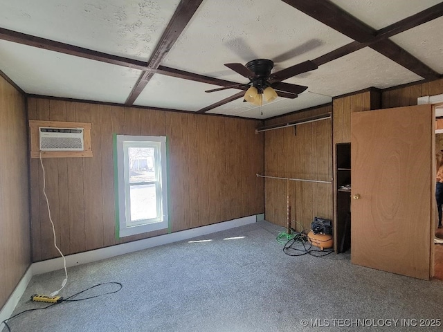 unfurnished room featuring coffered ceiling, wooden walls, a wall unit AC, beamed ceiling, and light colored carpet