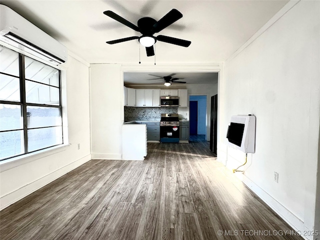 unfurnished living room with heating unit, a wall mounted air conditioner, and dark hardwood / wood-style floors