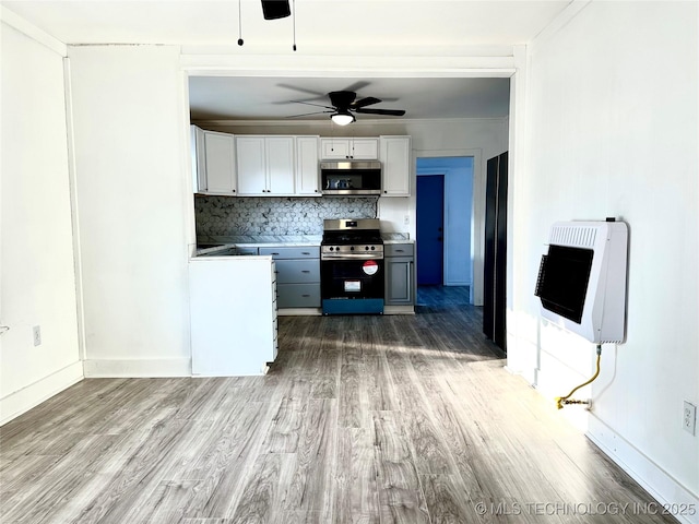 kitchen with hardwood / wood-style floors, heating unit, tasteful backsplash, white cabinets, and stainless steel appliances