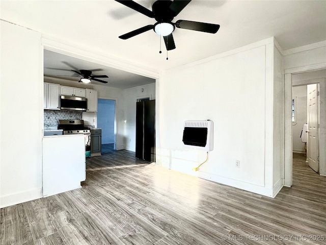 unfurnished living room with heating unit, hardwood / wood-style flooring, and ceiling fan