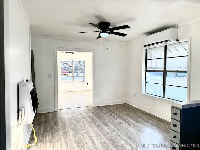 unfurnished room with heating unit, ceiling fan, wood-type flooring, and a wall unit AC