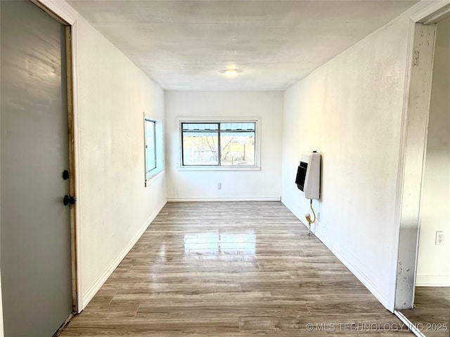 spare room featuring heating unit and light wood-type flooring