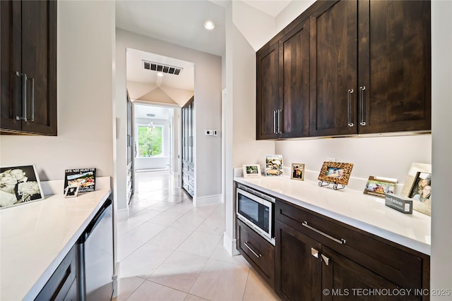 kitchen with dark brown cabinetry, light tile patterned floors, visible vents, stainless steel microwave, and light countertops