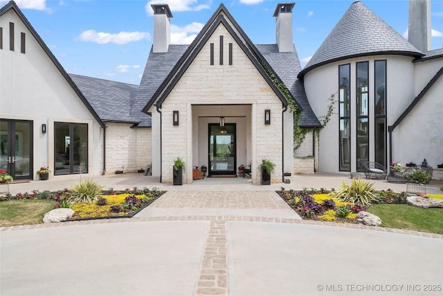 entrance to property with a high end roof, stone siding, and stucco siding