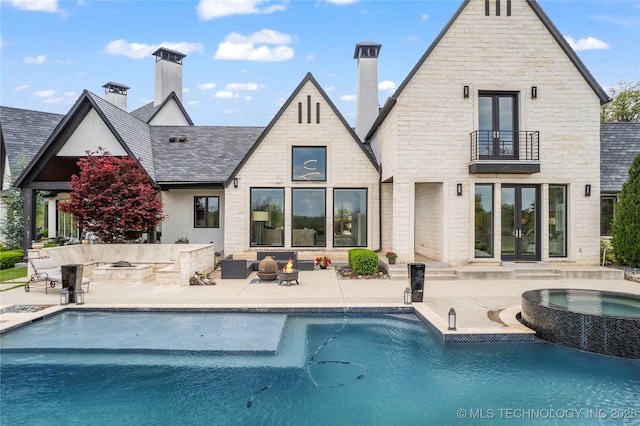 rear view of house with a balcony, an outdoor pool, a patio, and an in ground hot tub