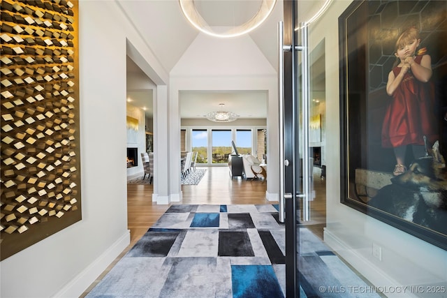 interior space featuring a towering ceiling, baseboards, and wood finished floors