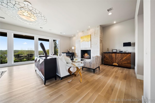 living room featuring light wood-type flooring, visible vents, a fireplace, and recessed lighting