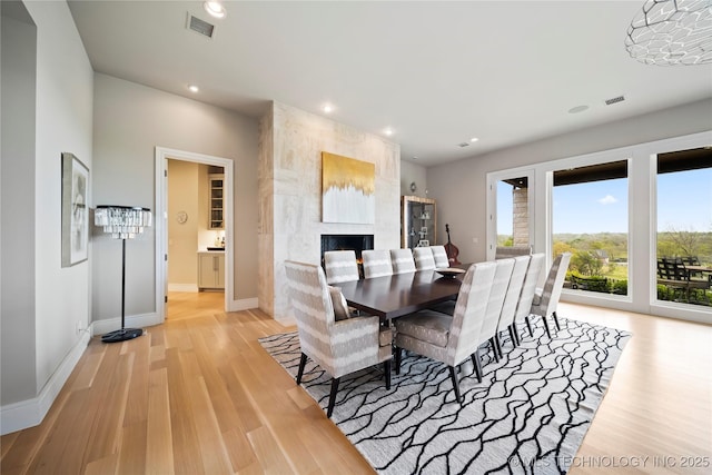 dining room with recessed lighting, visible vents, baseboards, light wood-style floors, and a tiled fireplace