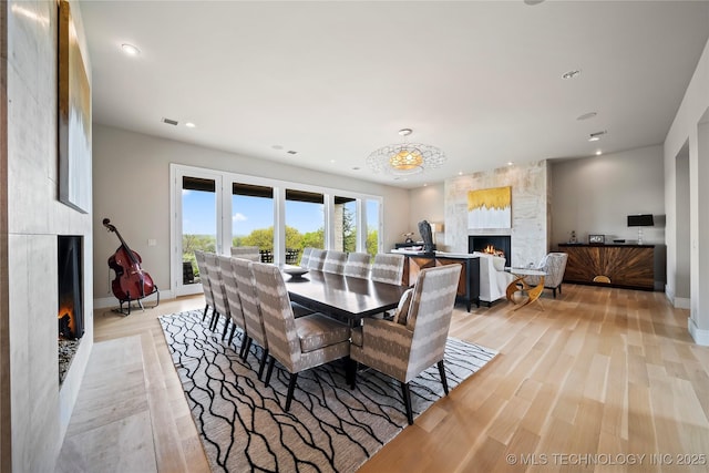 dining space with light wood-type flooring, a fireplace, baseboards, and recessed lighting