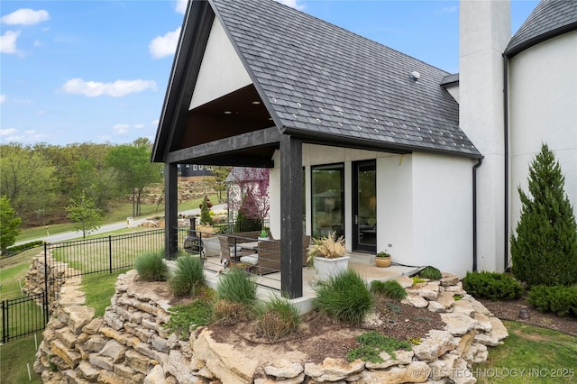 back of property featuring a chimney, a patio area, fence, and stucco siding