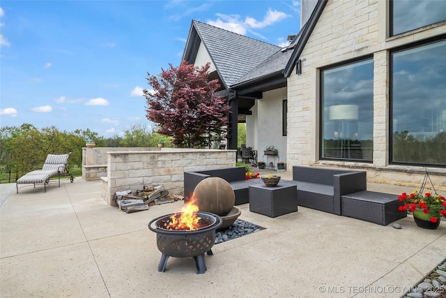 view of patio with an outdoor living space with a fire pit