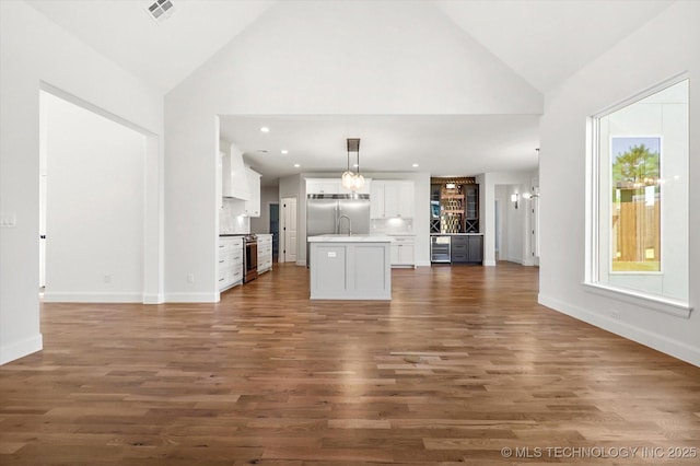 unfurnished living room featuring sink, dark hardwood / wood-style flooring, and high vaulted ceiling