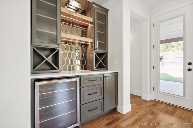 bar with wood-type flooring and beverage cooler