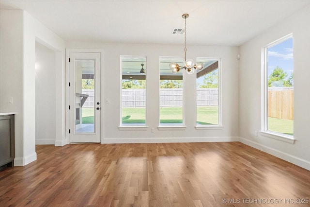 unfurnished dining area featuring wood-type flooring and an inviting chandelier