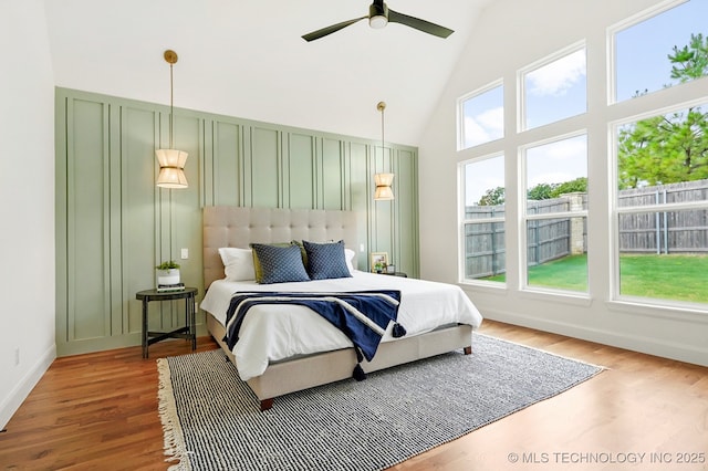 bedroom with hardwood / wood-style flooring, ceiling fan, and high vaulted ceiling