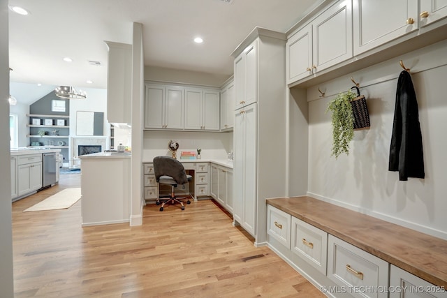 mudroom with lofted ceiling, built in desk, and light hardwood / wood-style flooring