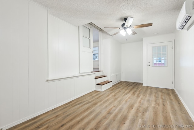 3006 E 21st St, Tulsa, OK 74114 - unfurnished room featuring an AC wall unit, wood finished floors, a textured ceiling, and healthy amount of natural light