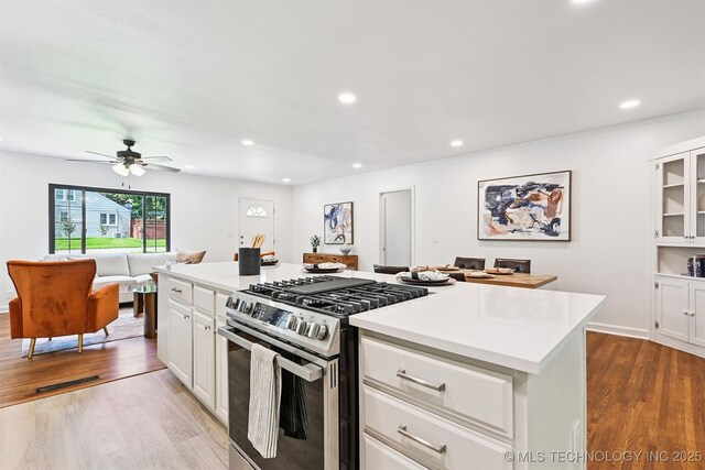 3006 E 21st St, Tulsa, OK 74114 - kitchen with stainless steel gas range, light countertops, white cabinets, wood finished floors, and open floor plan