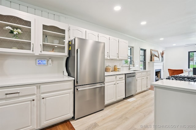 3006 E 21st St, Tulsa, OK 74114 - kitchen featuring appliances with stainless steel finishes, light wood-style flooring, white cabinets, glass insert cabinets, and light countertops