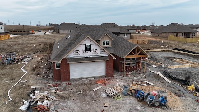 unfinished property featuring a garage, driveway, a shingled roof, and brick siding