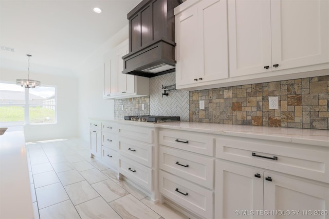 2044 E 129th Pl S, Jenks, OK 74037 - kitchen with custom range hood, backsplash, stainless steel gas stovetop, a chandelier, and white cabinetry