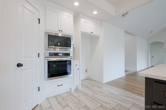 2044 E 129th Pl S, Jenks, OK 74037 - kitchen with appliances with stainless steel finishes, recessed lighting, white cabinets, light countertops, and arched walkways