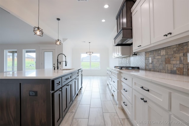 2044 E 129th Pl S, Jenks, OK 74037 - kitchen with a sink, decorative backsplash, a center island with sink, stainless steel gas cooktop, and white cabinetry