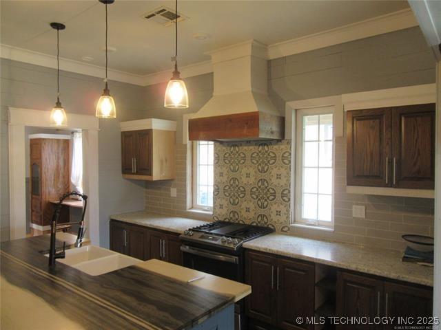 kitchen with dark brown cabinets, stainless steel range with gas cooktop, and premium range hood