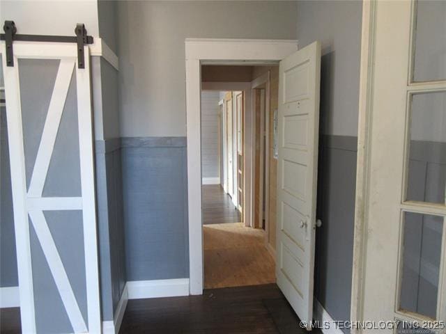 hall with a barn door and dark hardwood / wood-style floors