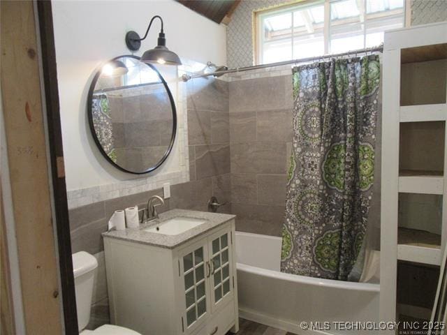 full bathroom with sink, tile walls, shower / bath combination with curtain, and toilet