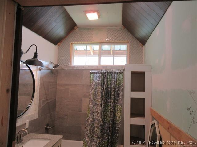 bathroom with lofted ceiling, sink, and shower / bathtub combination with curtain