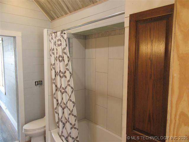 bathroom with vaulted ceiling, shower / tub combo, and toilet