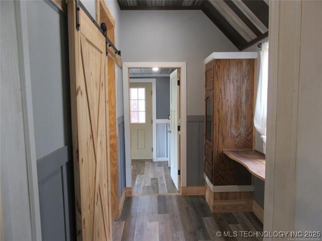 mudroom with lofted ceiling, hardwood / wood-style floors, and a barn door