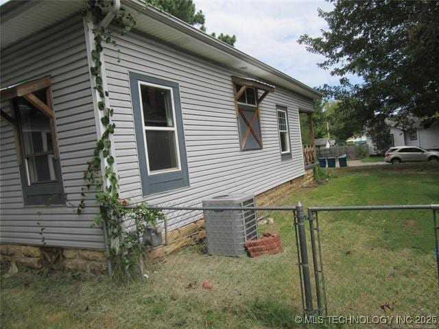 view of side of home with a yard and central AC unit