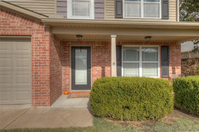 entrance to property with a garage, brick siding, and covered porch