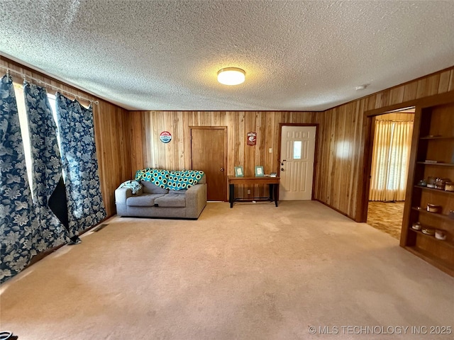 living area with wooden walls, carpet floors, and a textured ceiling