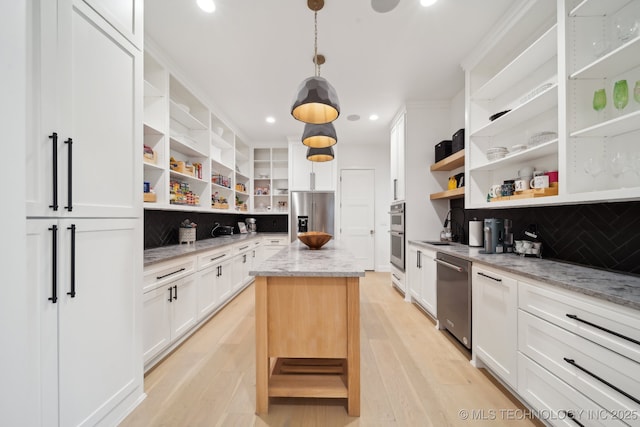 kitchen featuring a kitchen island, stainless steel appliances, white cabinets, and light stone counters