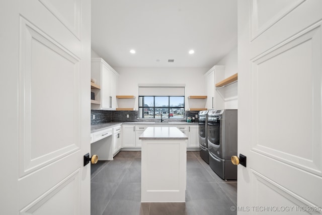 7300 E College St, Broken Arrow, OK 74014 - kitchen with open shelves, washer and clothes dryer, a center island, decorative backsplash, and white cabinets