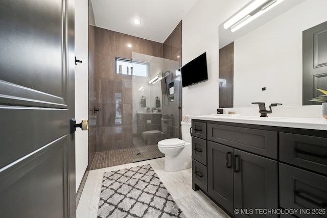 bathroom featuring toilet, vanity, and tiled shower