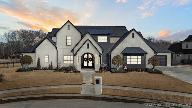 view of front of property featuring a standing seam roof, driveway, metal roof, and stucco siding