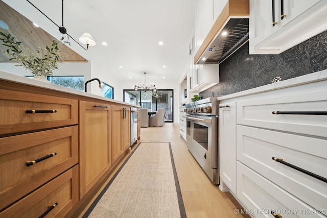 kitchen with pendant lighting, double oven range, white cabinets, and range hood