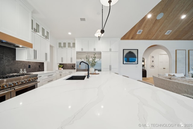 7300 E College St, Broken Arrow, OK 74014 - kitchen featuring a sink, double oven range, backsplash, glass insert cabinets, and arched walkways