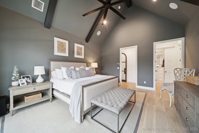 bedroom featuring beam ceiling, ensuite bath, high vaulted ceiling, light hardwood / wood-style floors, and ceiling fan